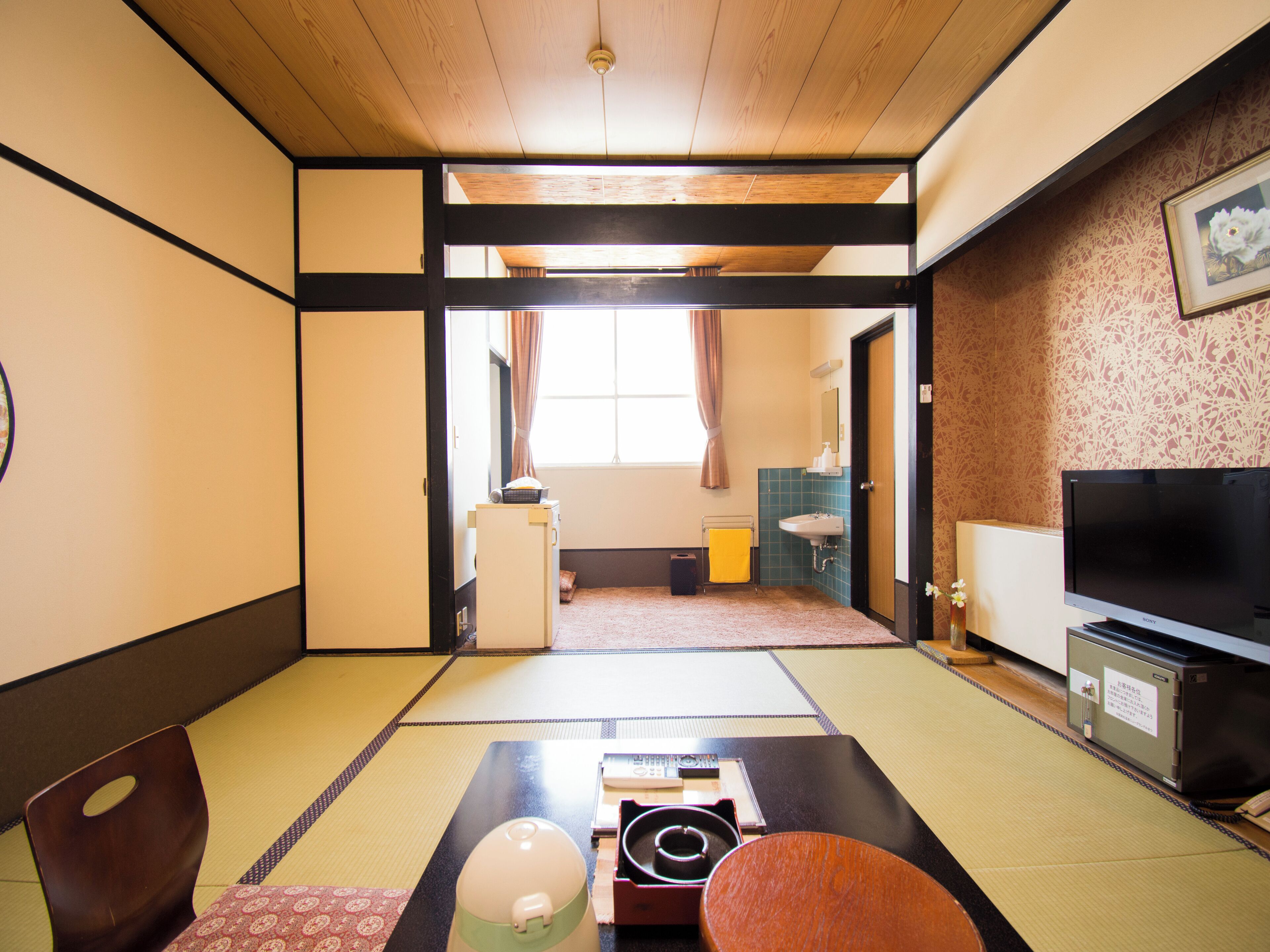 A traditional Japanese room with tatami flooring, a television, and a futon bed.