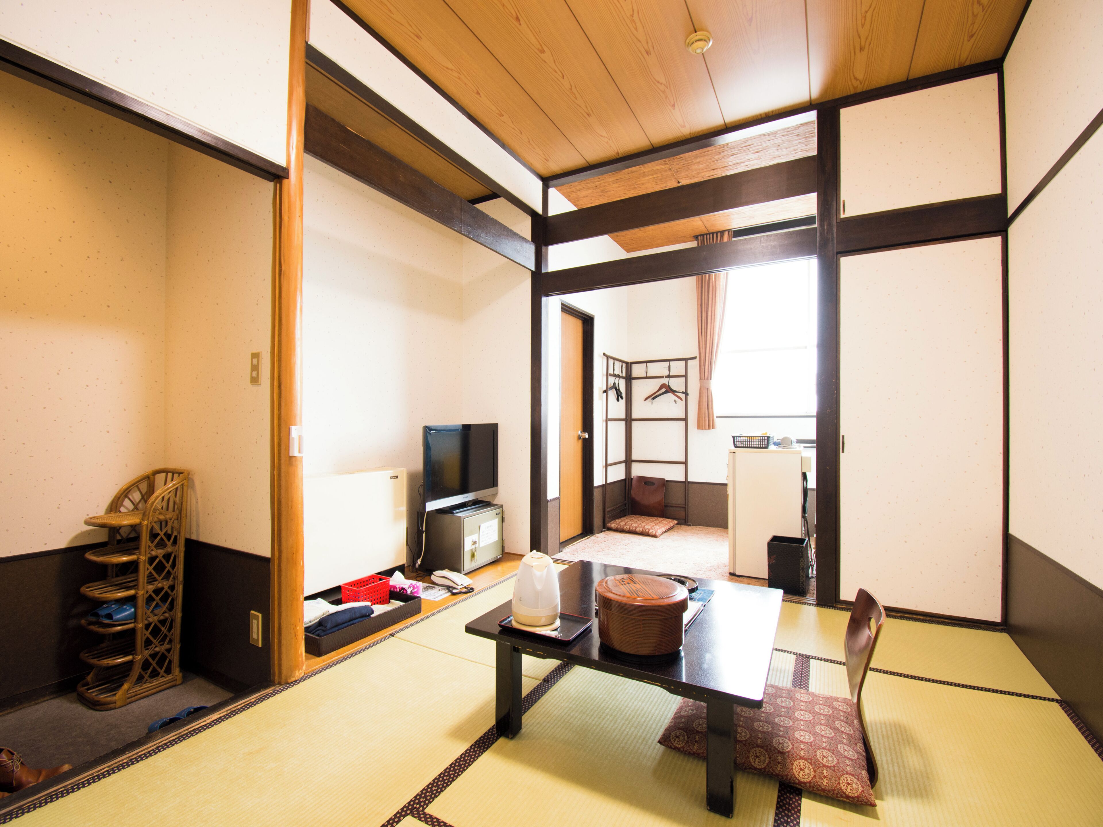A traditional Japanese room with tatami flooring, a low table, a television, and a futon bed.