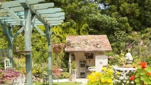 A garden with a pergola, a small house, and a stone pathway.