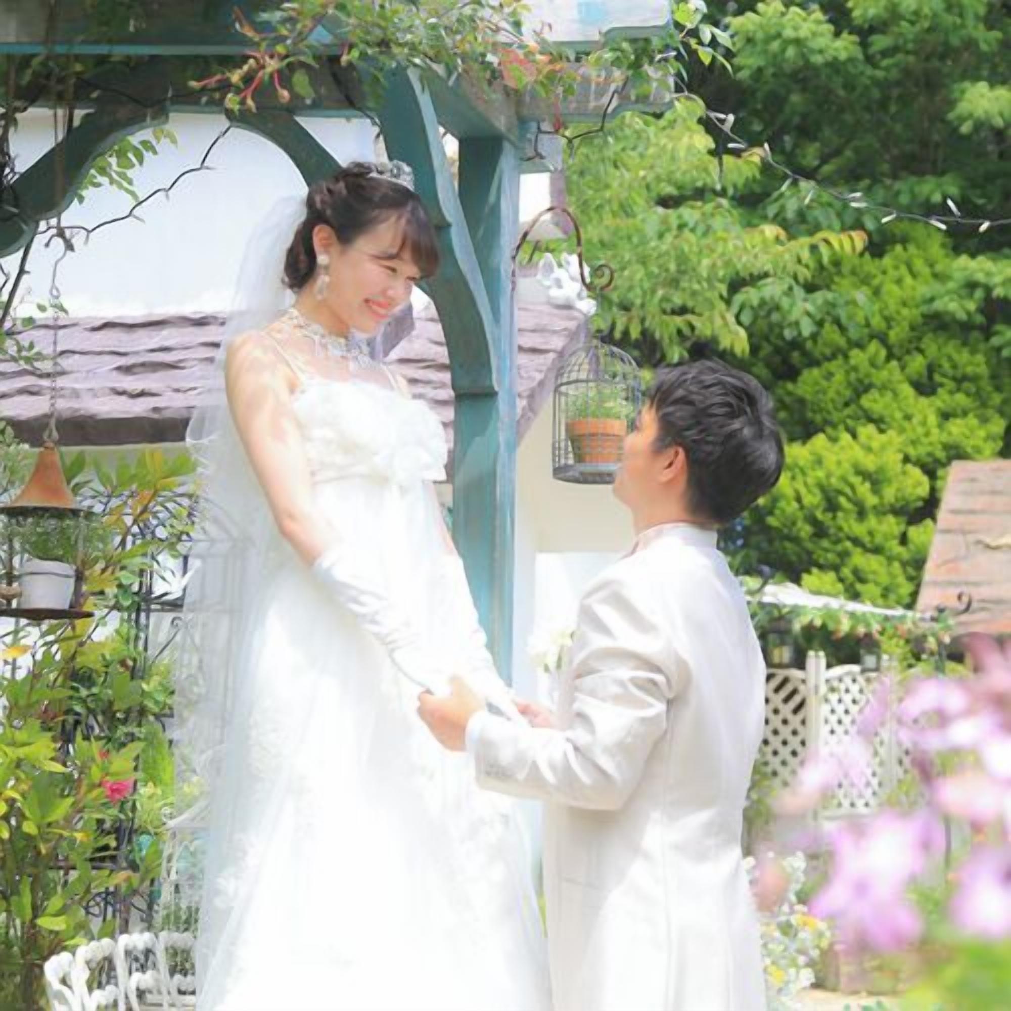 A wedding ceremony in a garden with a gazebo, greenery, and a birdcage.