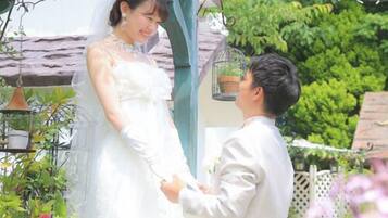 A wedding ceremony in a garden with a gazebo, greenery, and a birdcage.