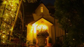 A house with a lit entrance, a visible window, and a potted plant in front. - Izukogen Hananomori Clarice (Ito)