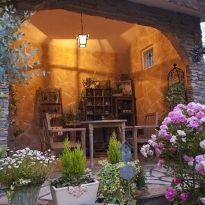 A cozy interior with a stone archway, wooden furniture, and potted plants. - Izukogen Hananomori Clarice (Ito)