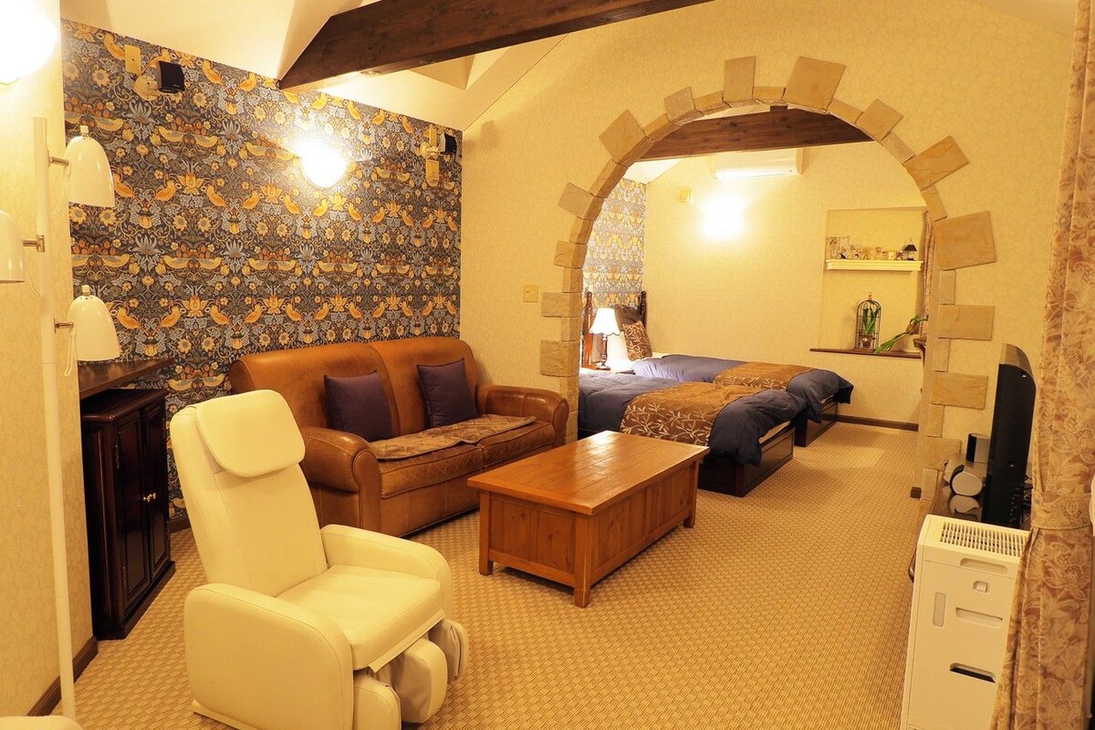 A cozy living room with a patterned wall, a leather sofa, a wooden coffee table, and a white armchair.