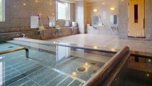 A modern spa with a glass-enclosed hot tub, granite walls, and wooden sauna doors. - New Royal Hotel Shimanto (Shimanto)