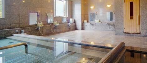 Un spa moderne doté d’un jacuzzi à ciel ouvert, de murs en granit et de portes de sauna en bois.
