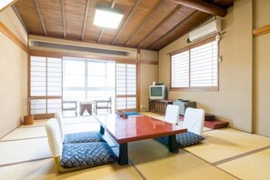 A tatami mat room with a low table, chairs, a television, and sliding doors. - Shinshu Shimosuwa Onsen Gingetsu (Suwa)