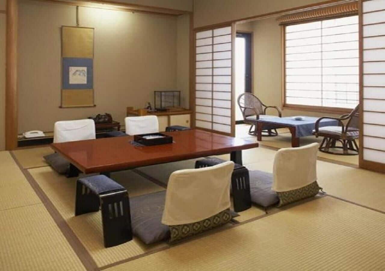 Ein traditioneller japanischer Raum mit Tatami-Bodenbelag, einem niedrigen Holztisch und vier Tatami-Zusatzkissen.