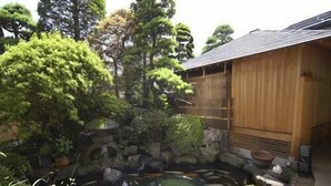 A traditional Japanese garden with a koi pond, stone lanterns, and a wooden building.