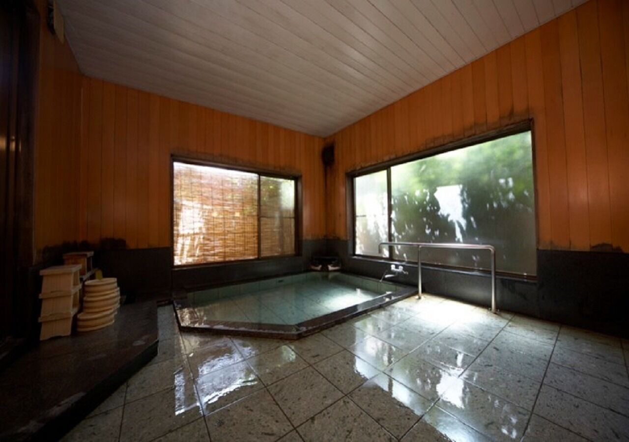 A room with a hot tub, wooden walls, and large windows.
