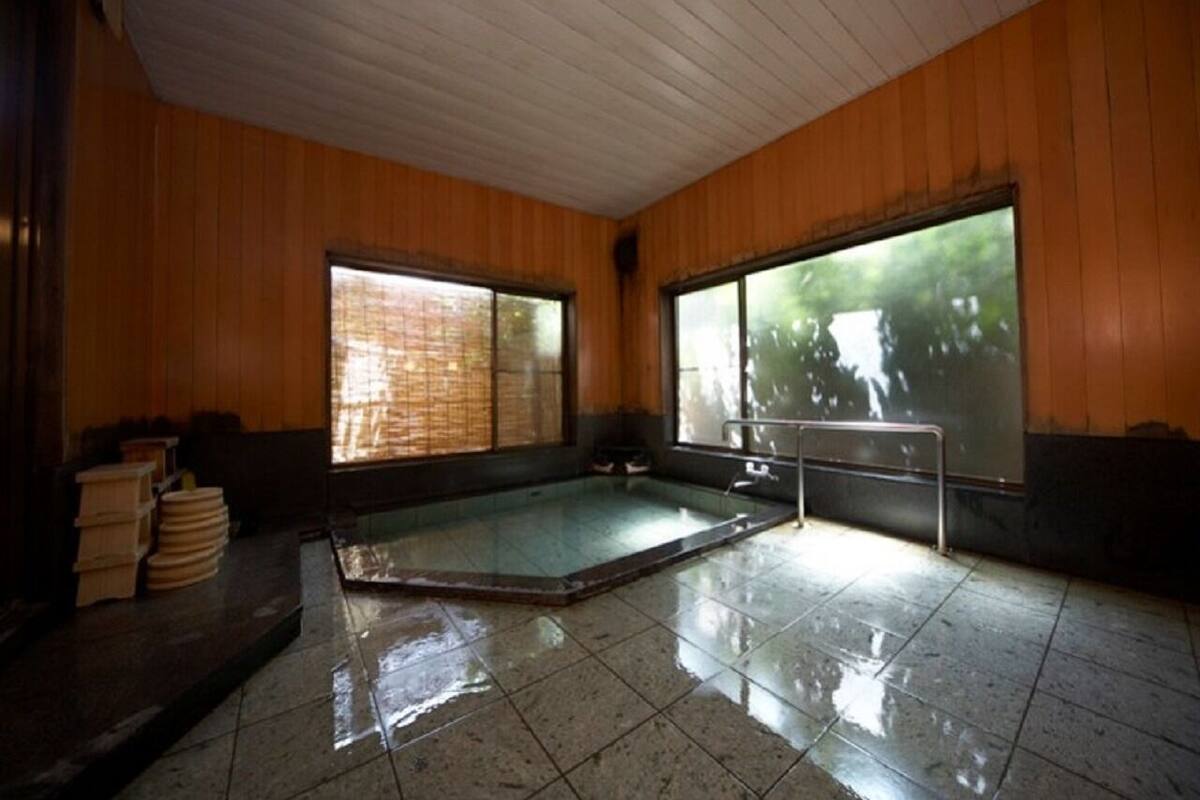 A room with a hot tub, wooden walls, and large windows.