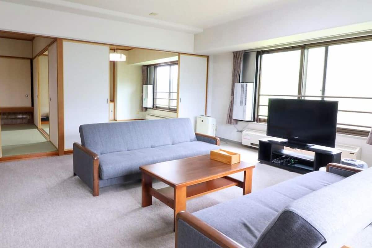 A living room with a sofa, a coffee table, a TV, and a sliding door leading to a bathroom.