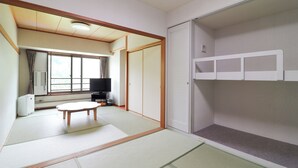 Quarto com piso de tatame, cama futon, televisão e armário com portas deslizantes.