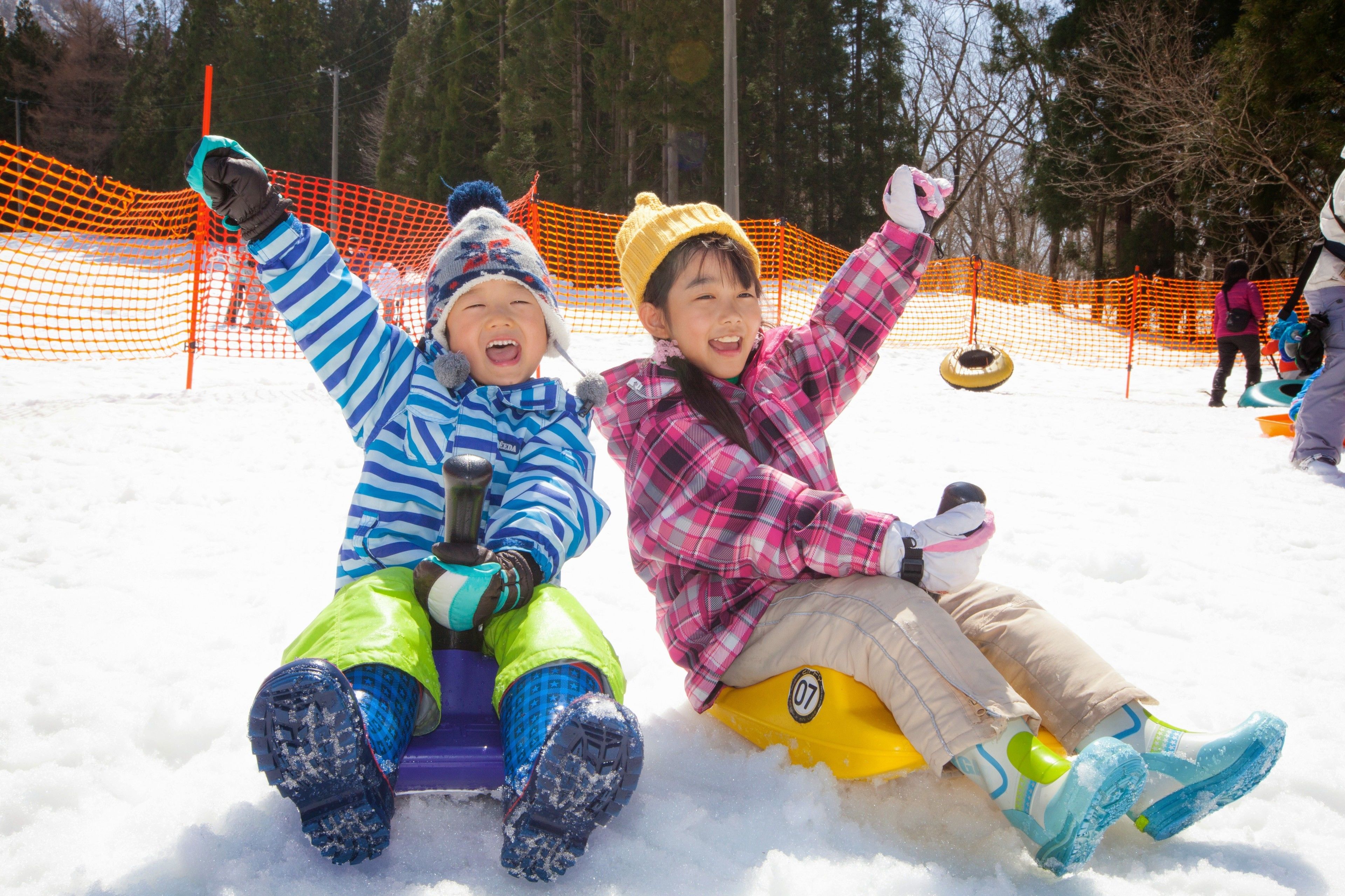 Two children sledding on snow tubes.