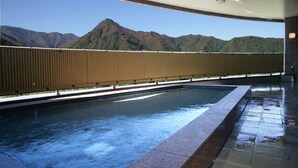 Piscina com vista para montanhas, área coberta com teto e piso de azulejos.