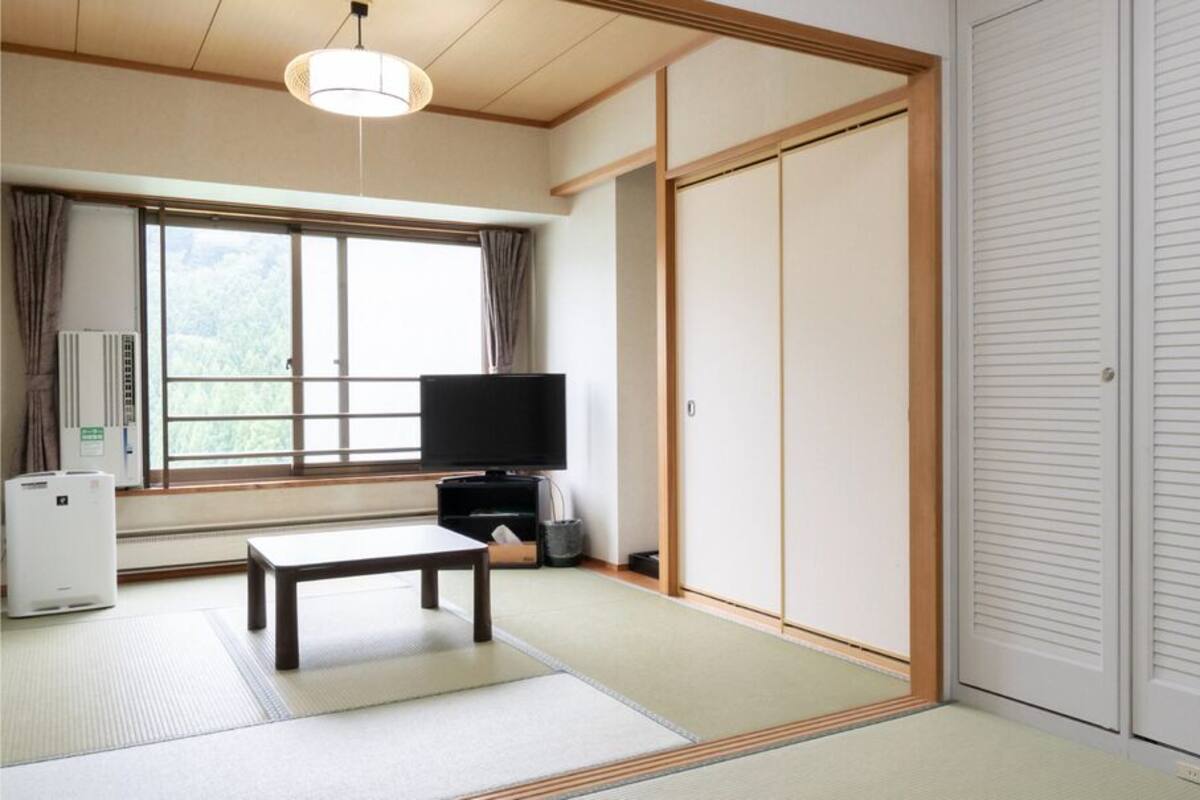 A traditional Japanese room with tatami flooring, a television, a heater, and sliding doors.