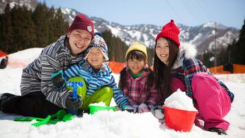 A family of four in a snowy outdoor setting with mountains in the background.
