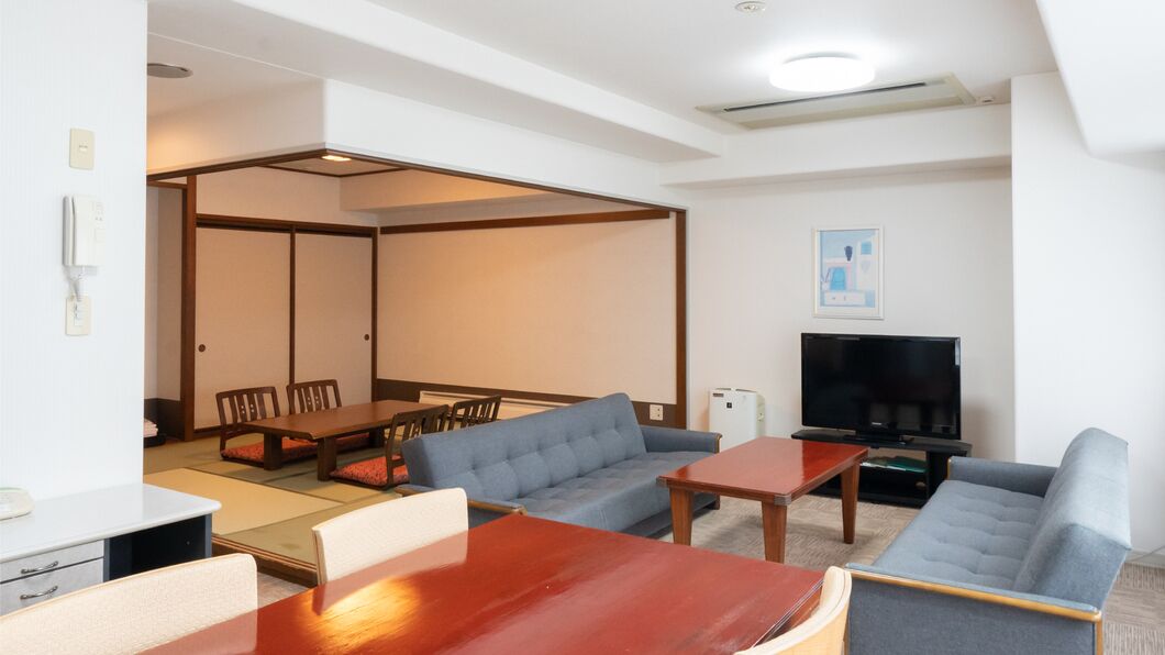 Un salon moderne comprenant un canapé, une table basse, un téléviseur et un coin repas avec des chaises et une table.