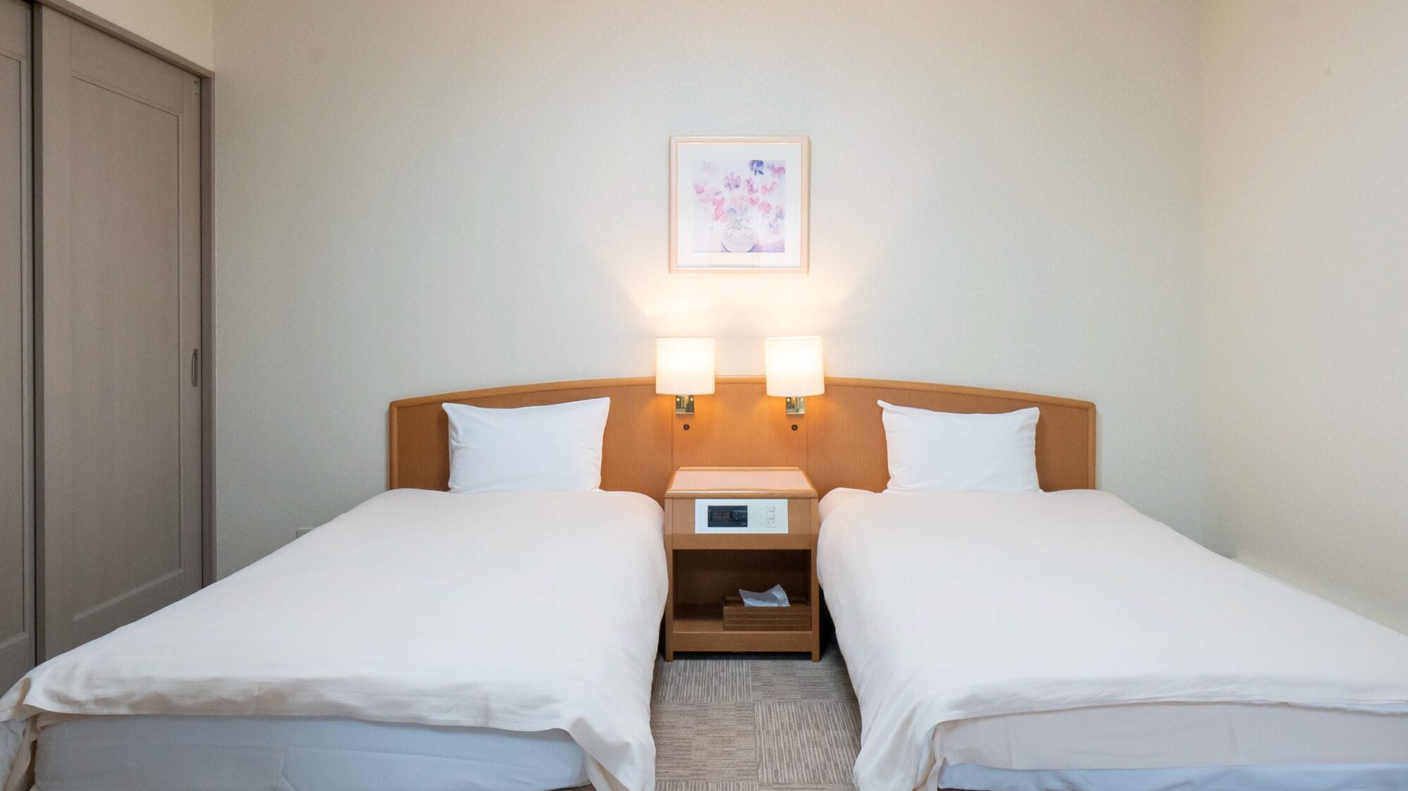 A double bed with two bedside tables, a clock, and a framed picture on the wall.