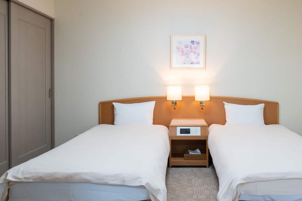 A double bed with two bedside tables, a clock, and a framed picture on the wall.