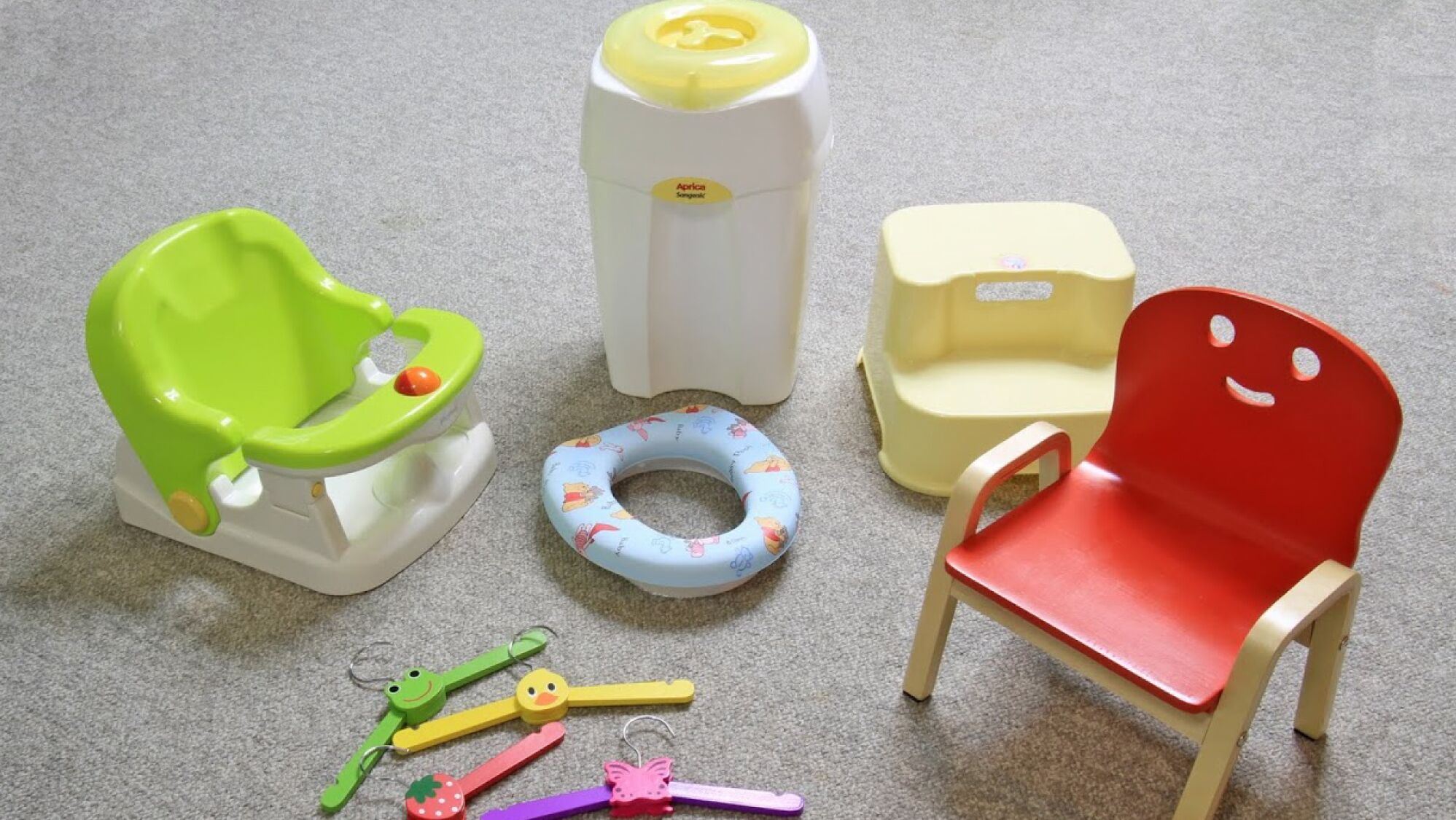A child's potty, a toilet seat, a chair, and a toilet paper holder.