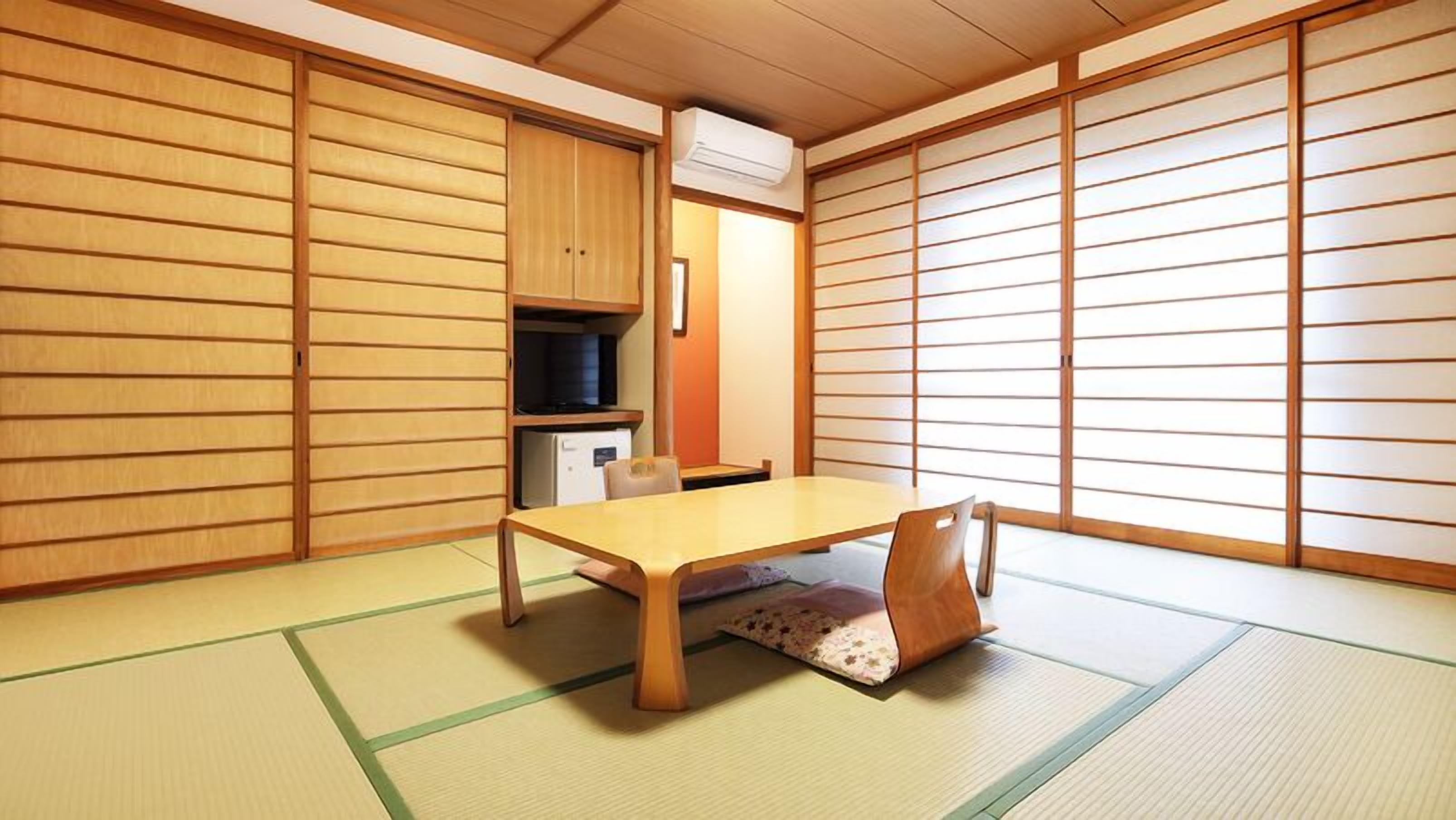 Una habitación japonesa tradicional con suelo de tatami, una mesa baja y puertas correderas.