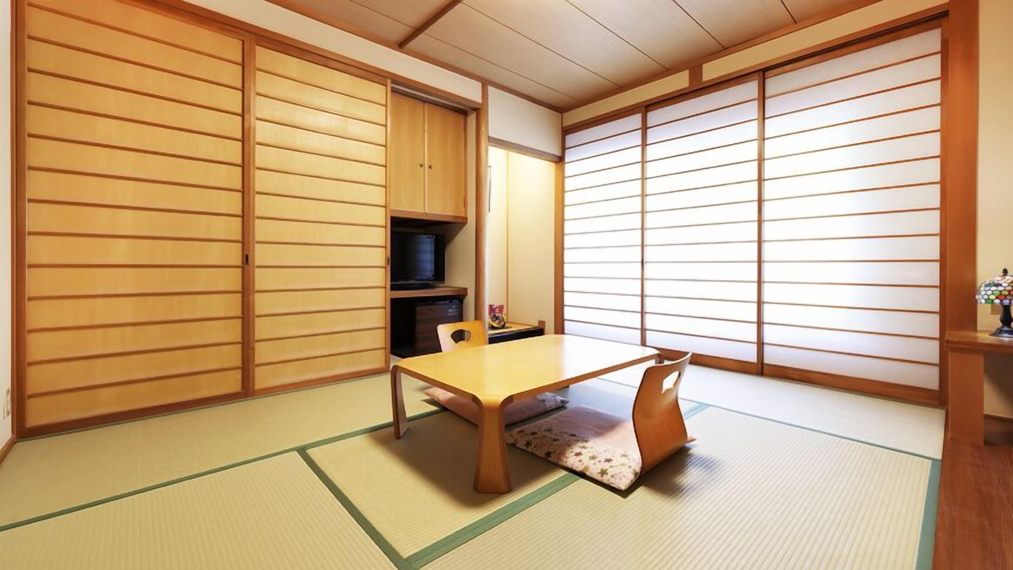 Una habitación japonesa tradicional con suelo de tatami, una mesa baja y puertas correderas.