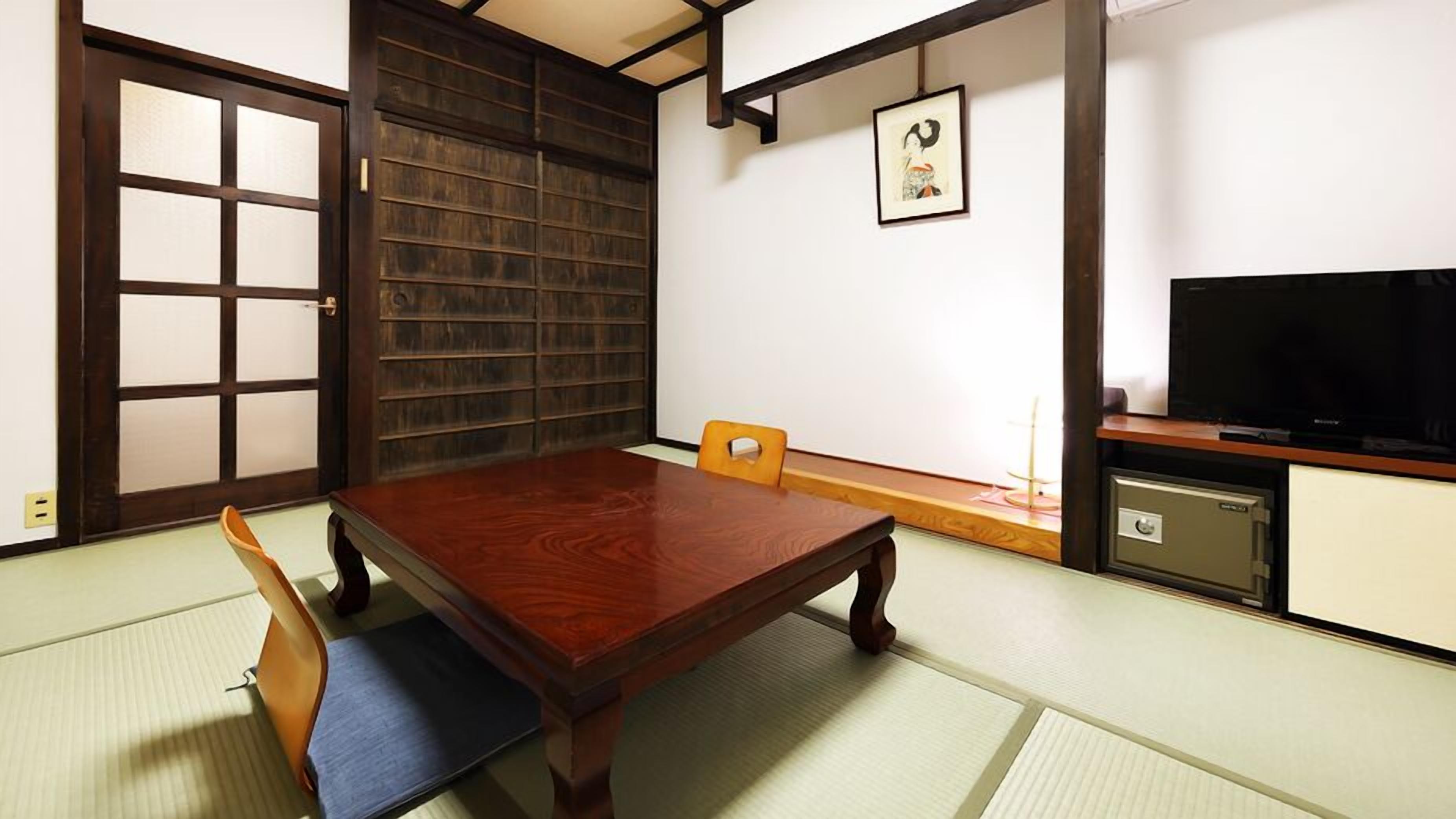 Una habitación japonesa tradicional con suelo de tatami, una mesa de madera baja y un televisor.