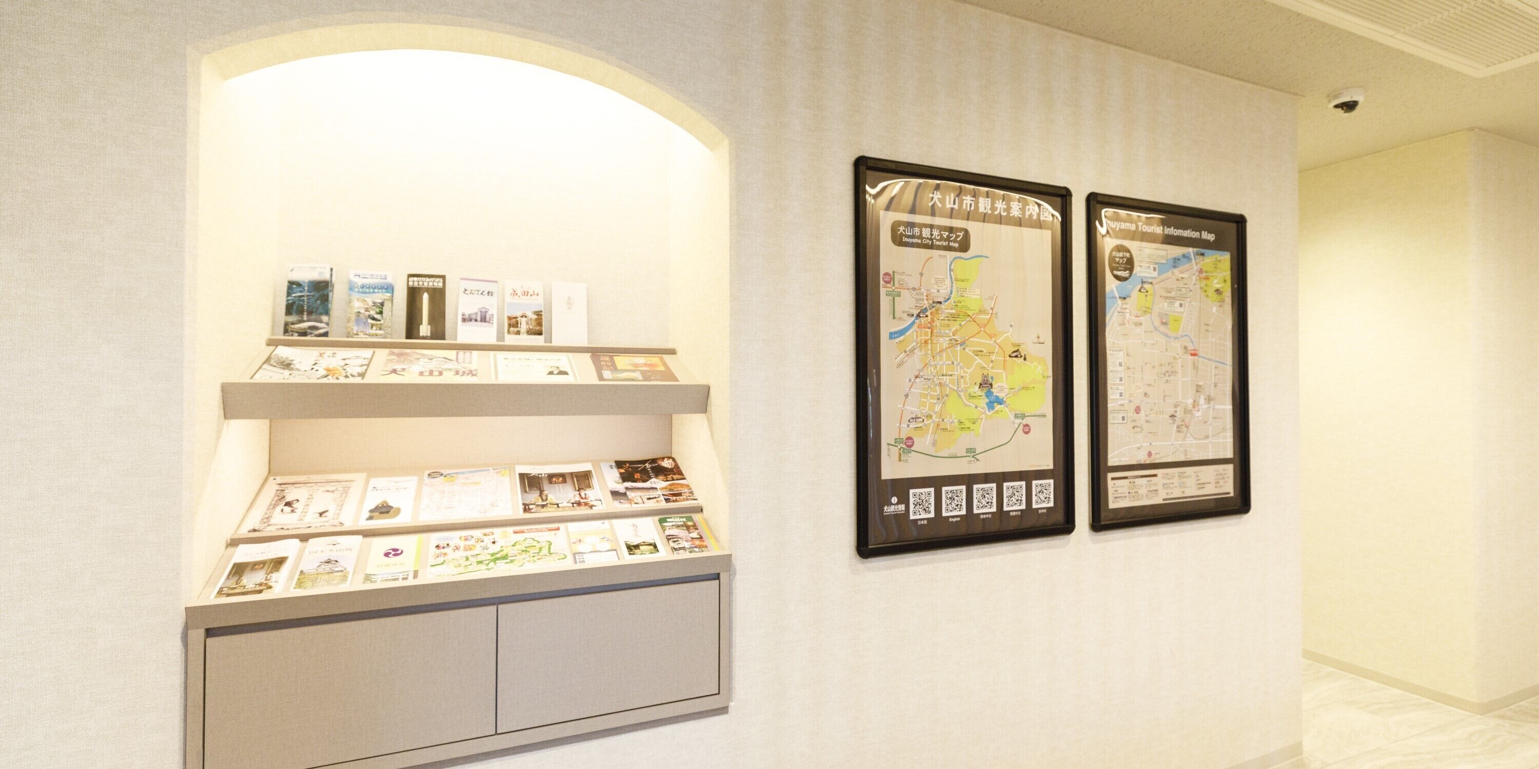 A hallway with two framed maps and a display case with informational brochures.