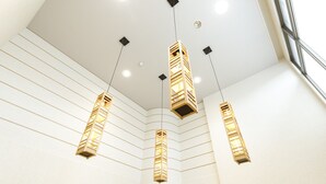 Ein modernes Interieur mit drei hängenden Holzkörperlampen und einer geneigten Decke.