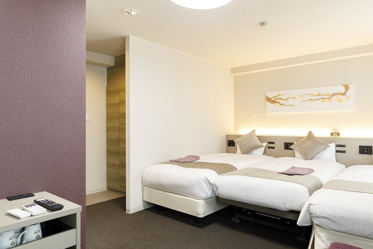 Ein Hotelzimmer mit zwei Betten, einem kleinen Tisch mit einer Fernbedienung und einem Wandbild.