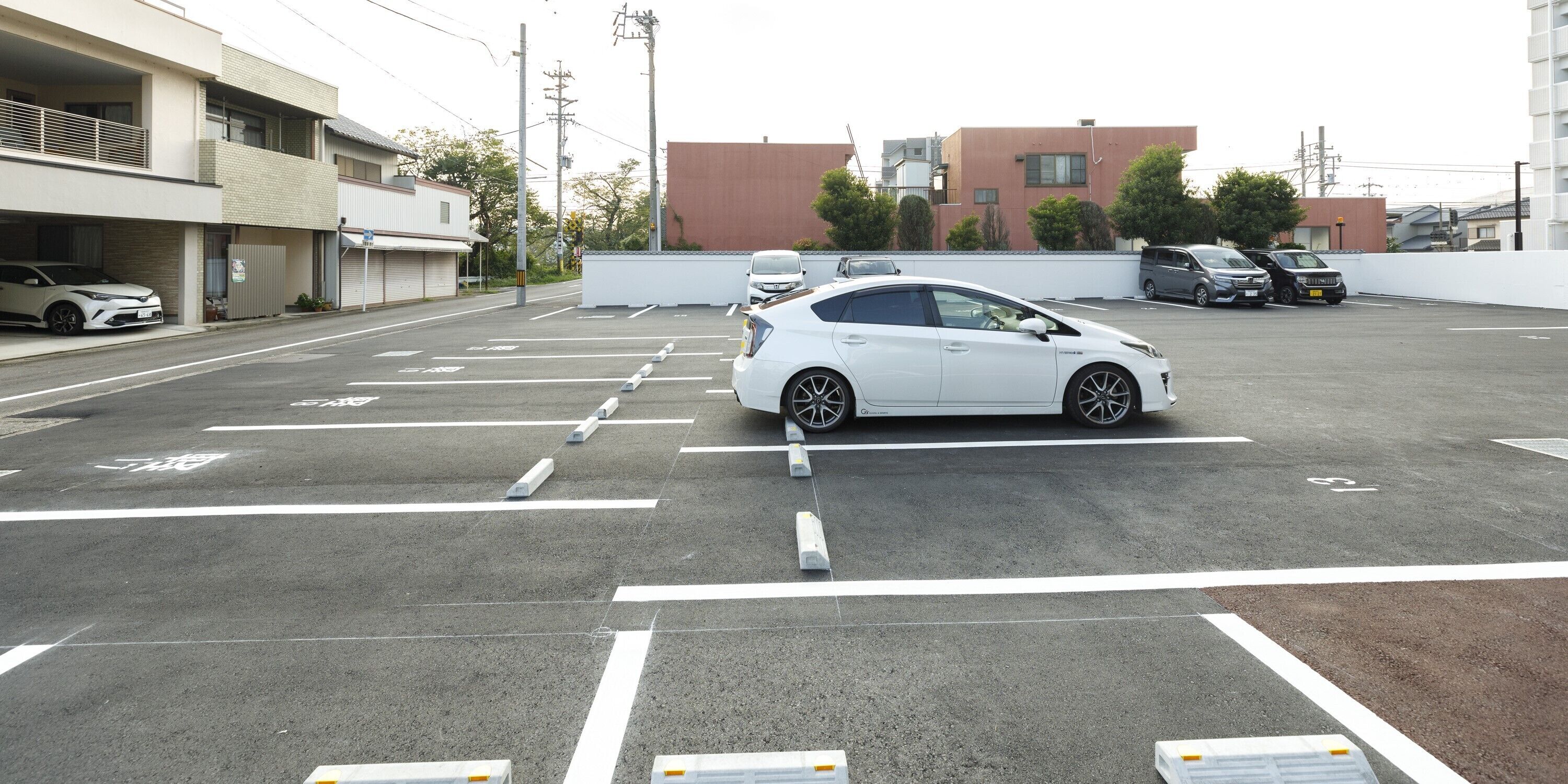 A parking lot with multiple cars, including a white sedan and a black SUV.