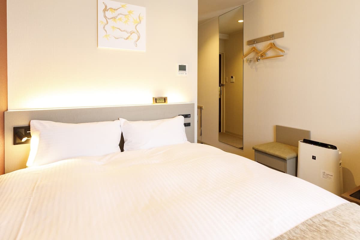 Ein Hotelzimmer mit Bett, Nachttisch und Spiegel.