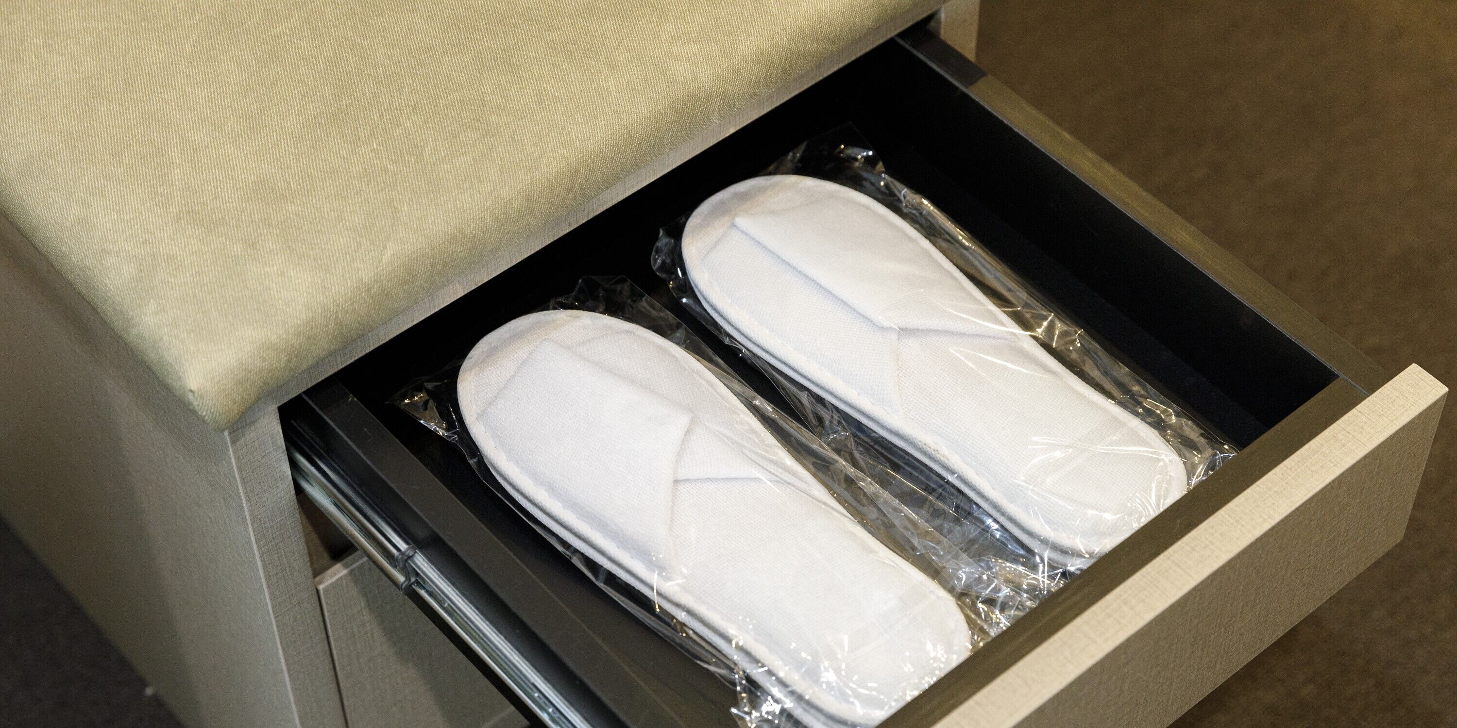 A drawer containing two white shoes wrapped in plastic.