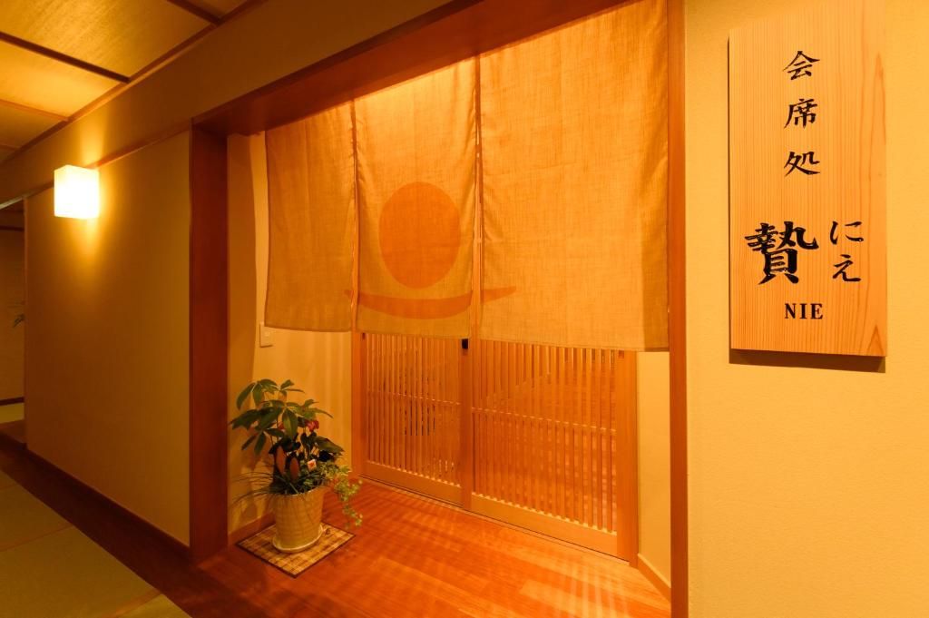 A traditional Japanese room with sliding doors, a potted plant, and a sign with Japanese characters.