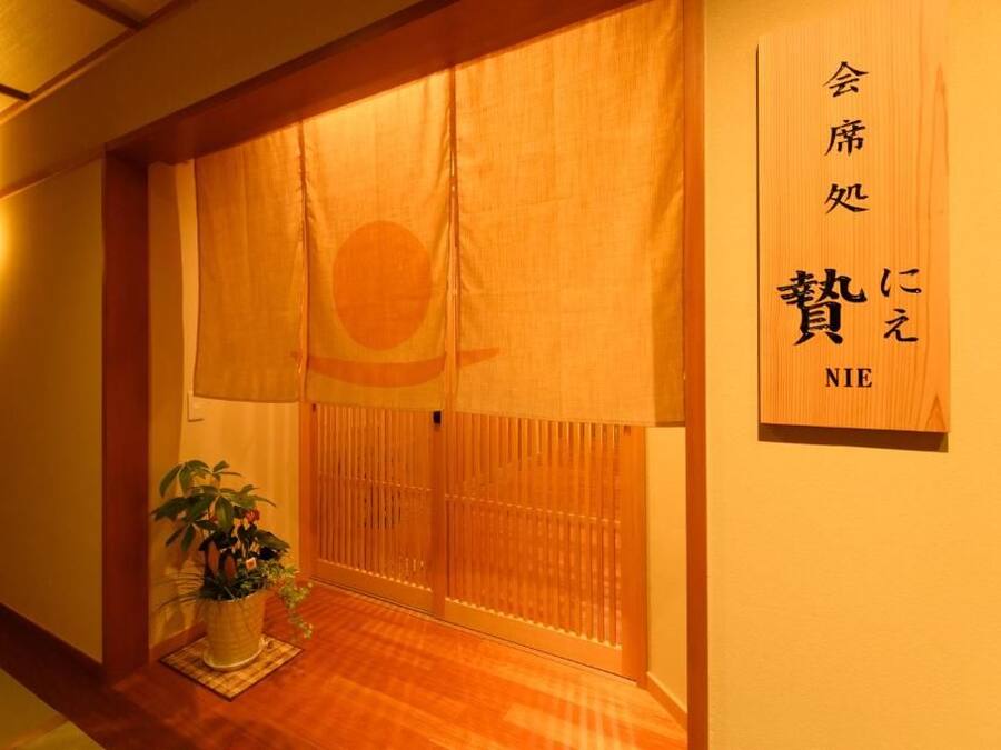 A traditional Japanese room with sliding doors, a potted plant, and a sign with Japanese characters.