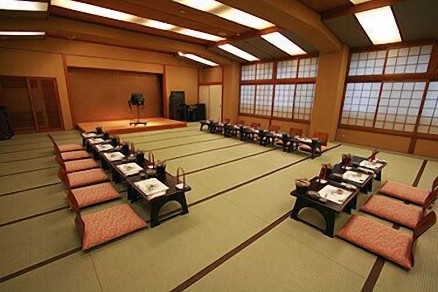 A traditional Japanese-style room with tatami mats, low tables, and cushions.