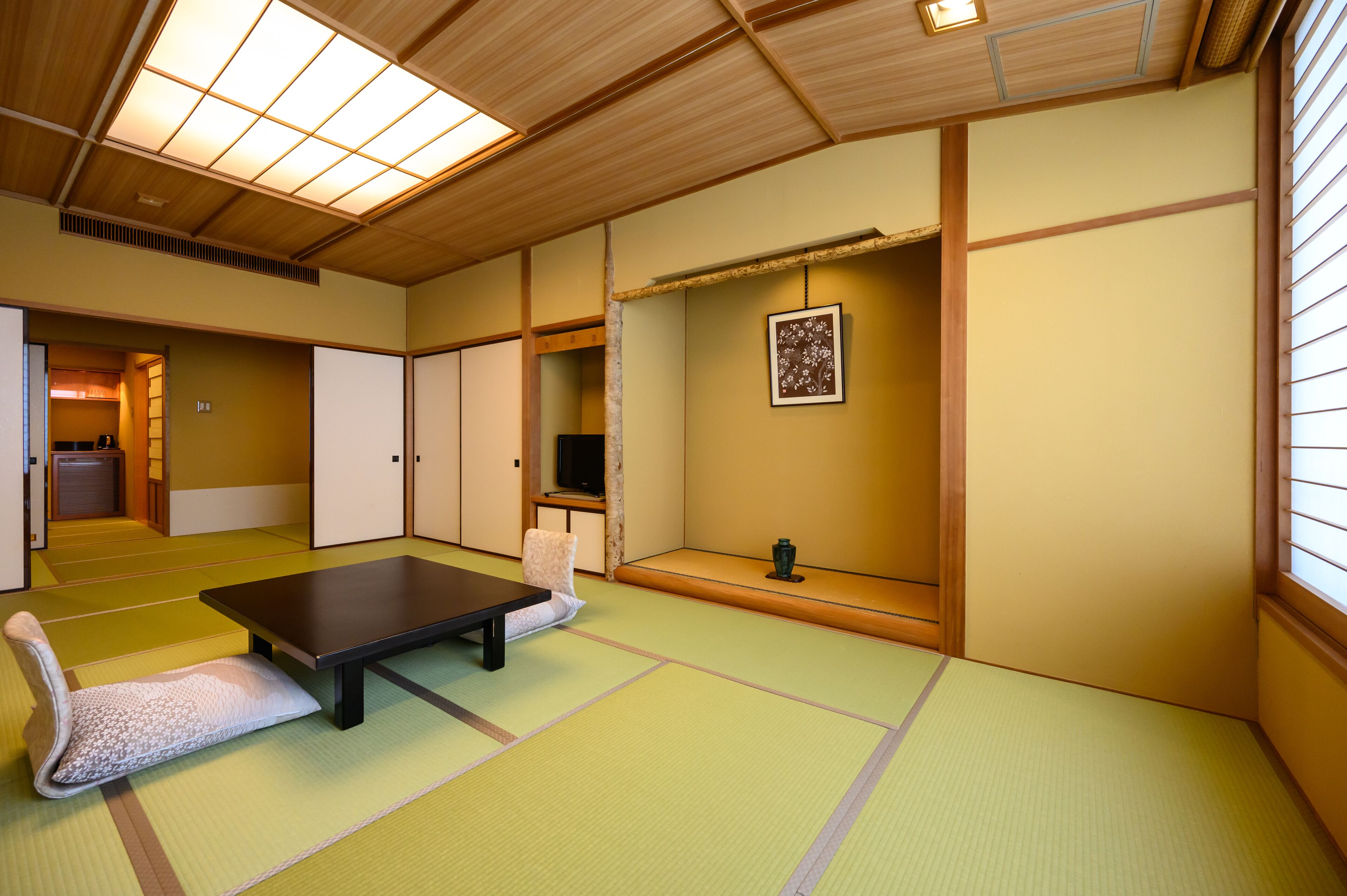 Una habitación japonesa tradicional con suelo de tatami, una mesita baja, un cojín y puertas correderas.