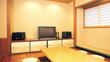 Una habitación con una mesa de madera, una televisión y altavoces sobre un mueble.