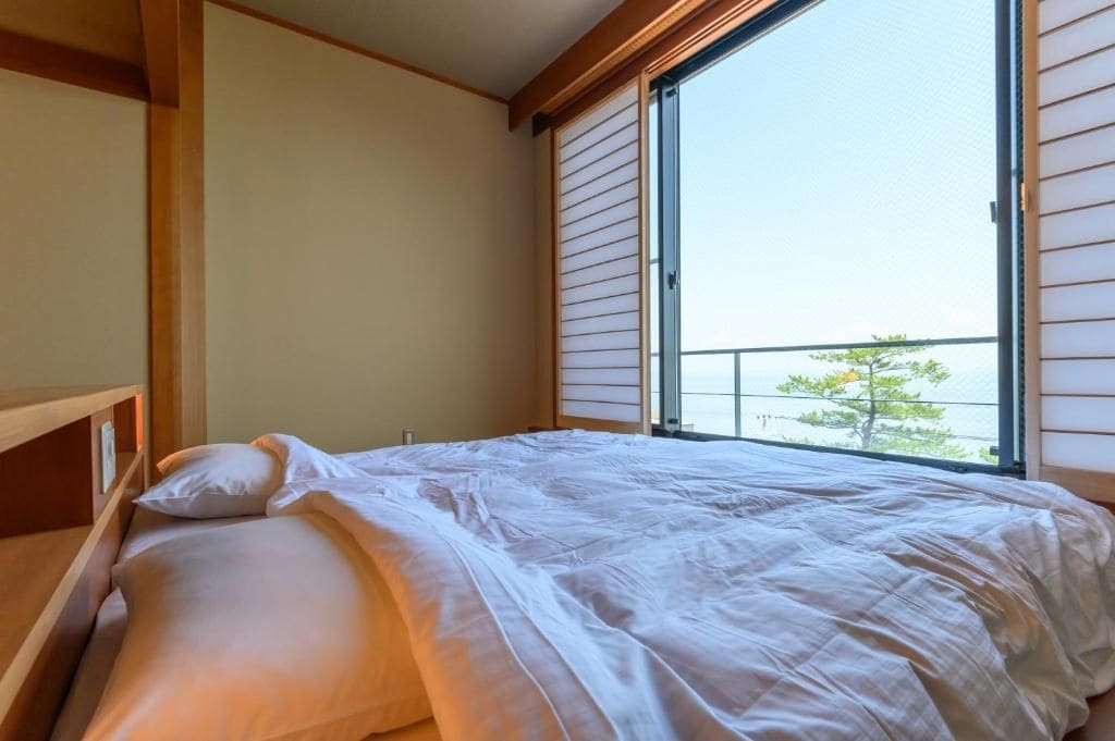 A bedroom with a bed, a window, and a view of the outdoors.