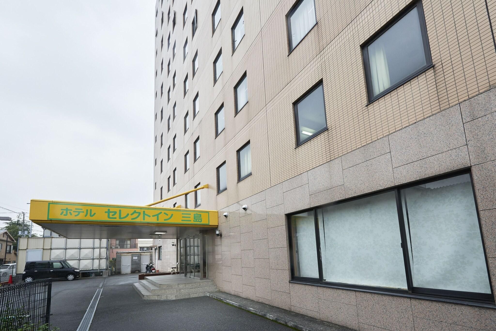 Entrada de hotel con un letrero, un corredor cubierto y un área de estacionamiento.