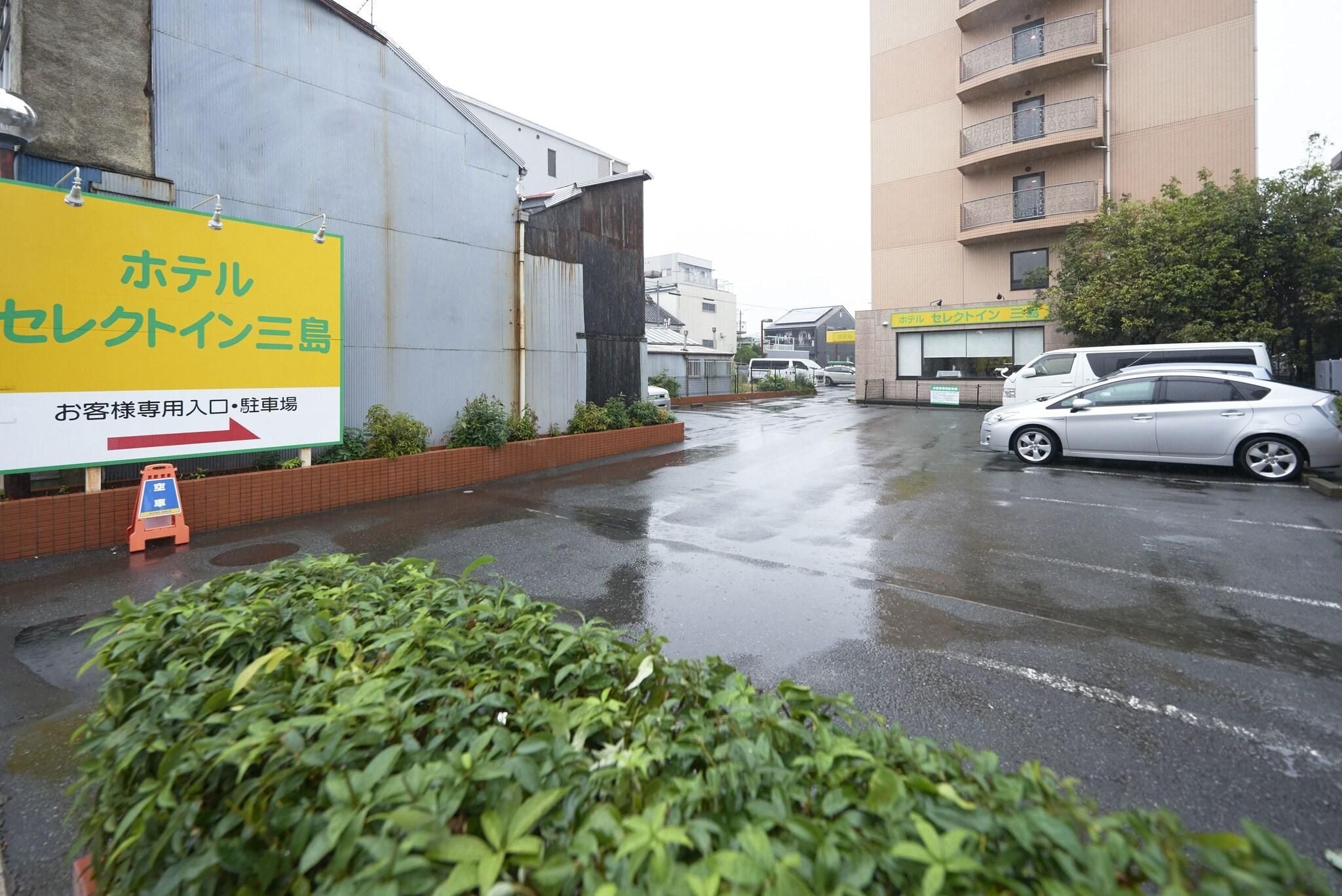 A hotel with a large signboard, a parking lot, and a building in the background.