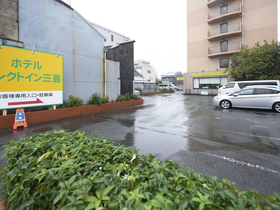 Un hotel con un letrero grande, un estacionamiento y un edificio al fondo.