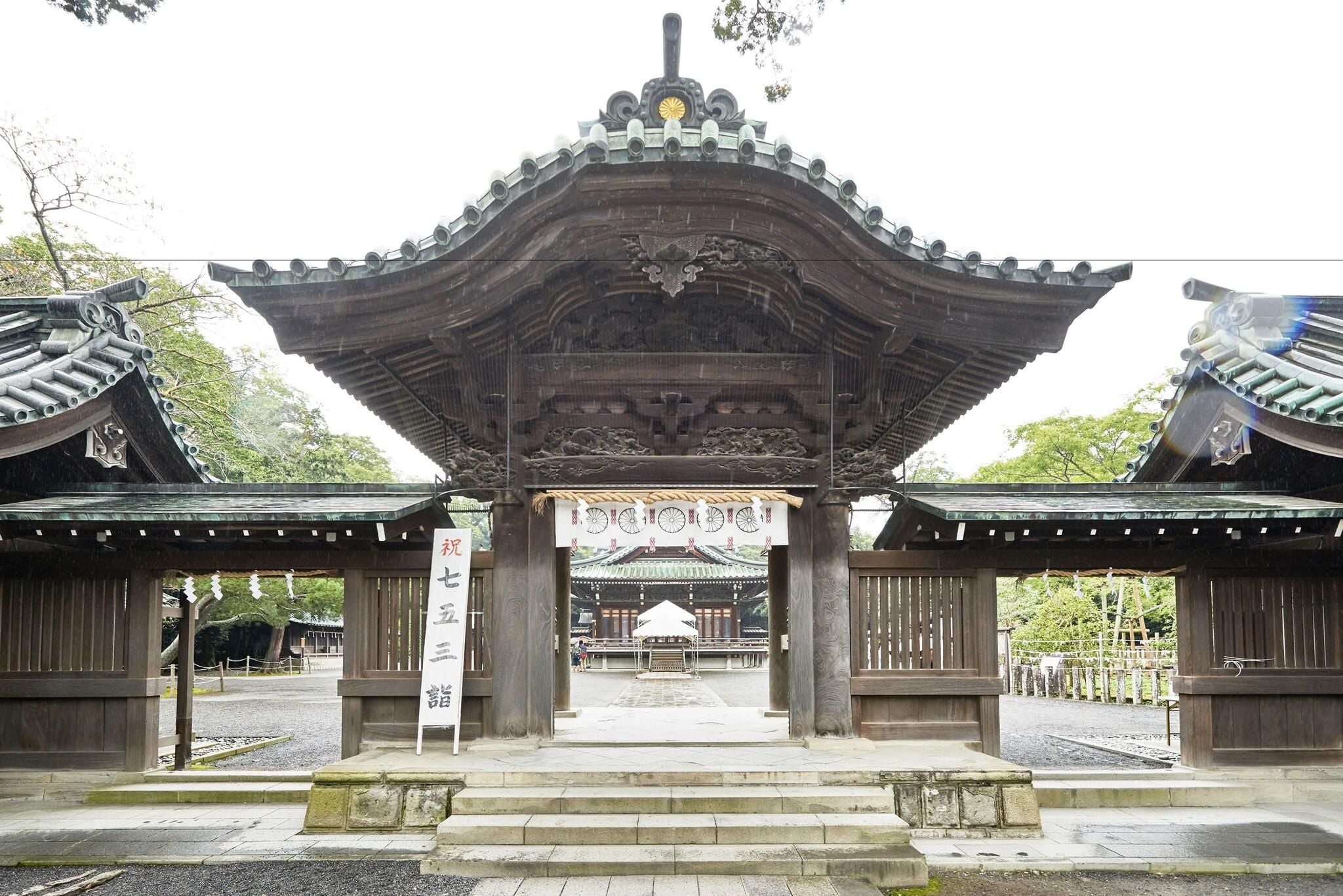 A traditional Japanese gate with intricate woodwork and a central emblem.