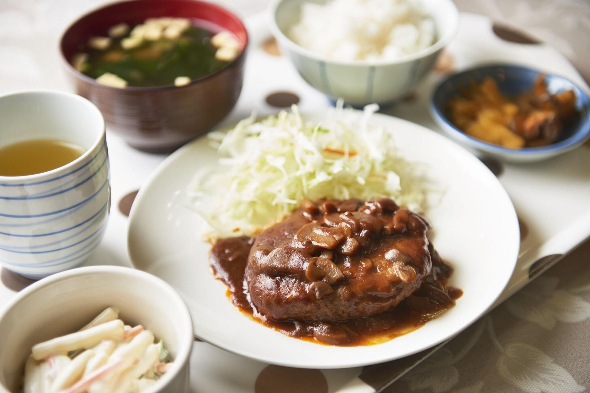 Un plato de comida con un guiso de carne, un tazón de sopa y una taza de té.