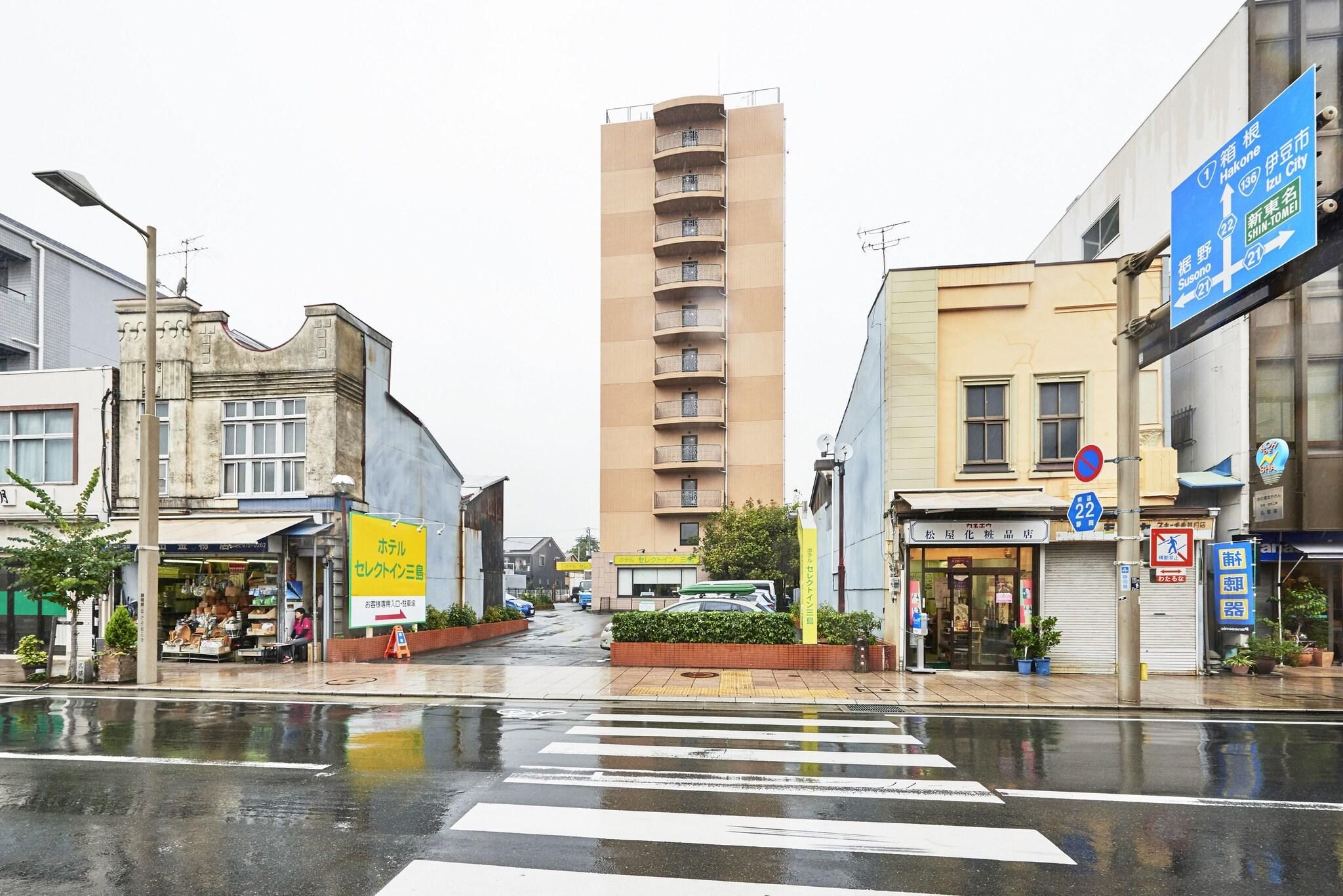 A street view with a crosswalk, buildings, and a tall apartment building.