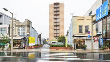 A street view with a crosswalk, buildings, and a tall apartment building.