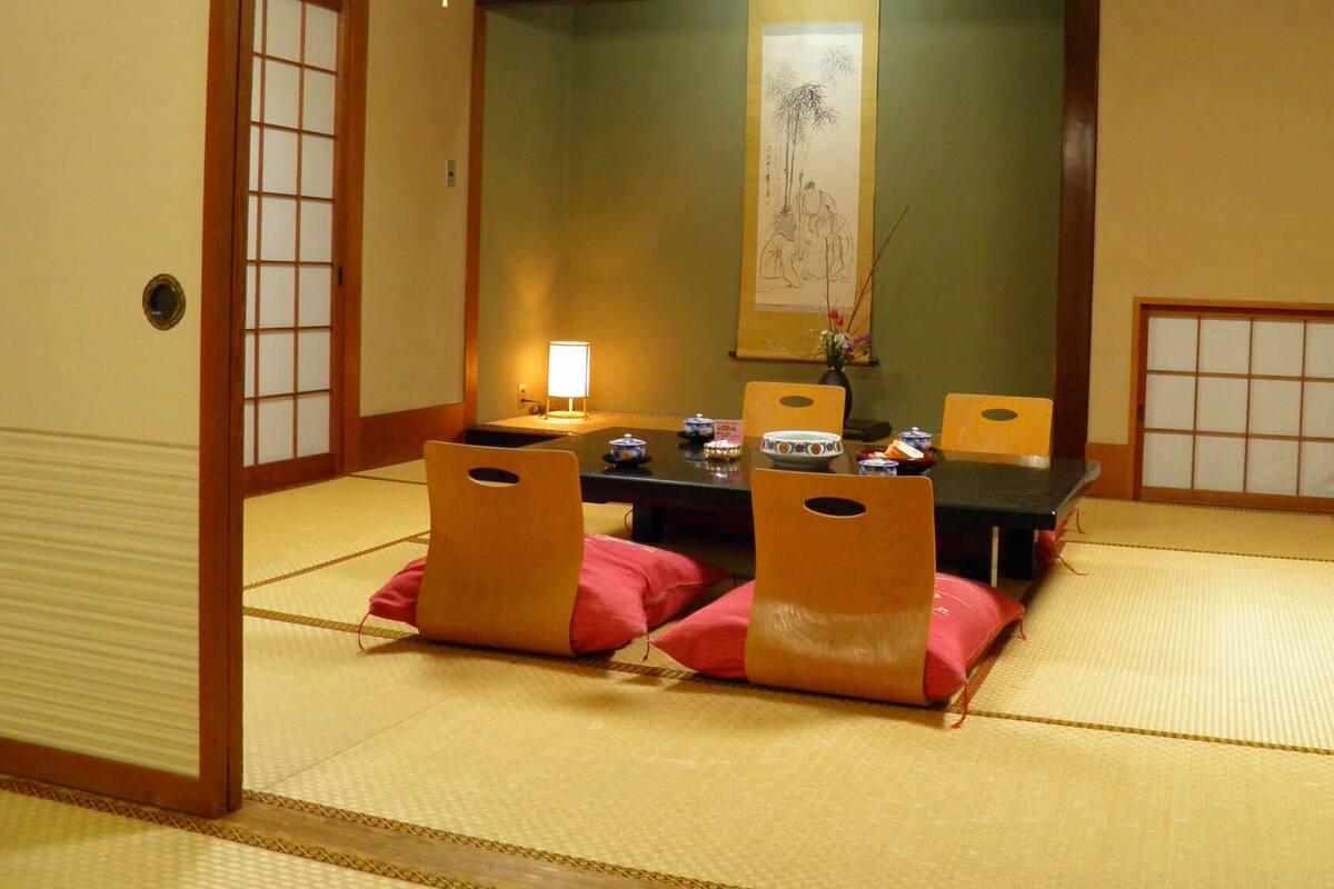 A traditional Japanese room with tatami flooring, a low table with cushions, and sliding doors.