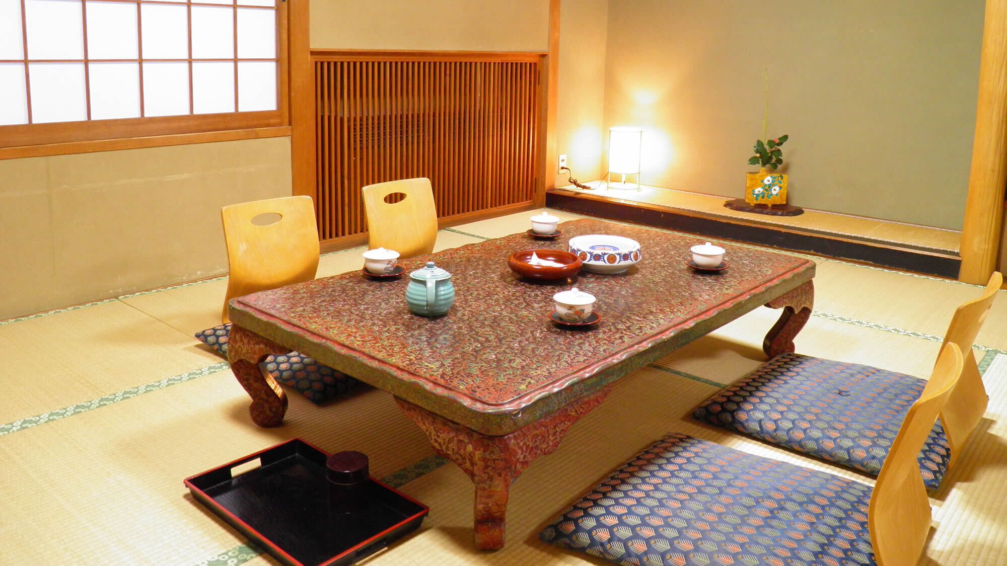 Une pièce traditionnelle japonaise avec un sol recouvert de tatamis, une table basse, des coussins et les ustensiles nécessaires à la cérémonie du thé.