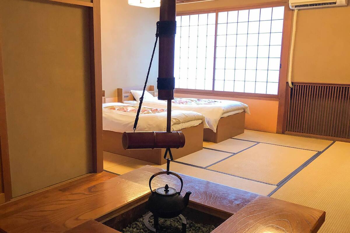 A traditional Japanese room with tatami flooring, a futon bed, a tea kettle, and a sliding door.